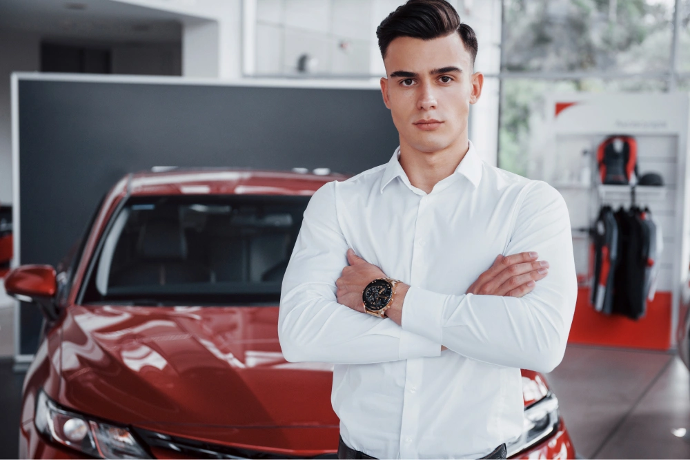 a-handsome-man-is-a-buyer-standing-next-to-a-new-car-at-the-dealer-center-and-looking-at-the-camera 1.jpg